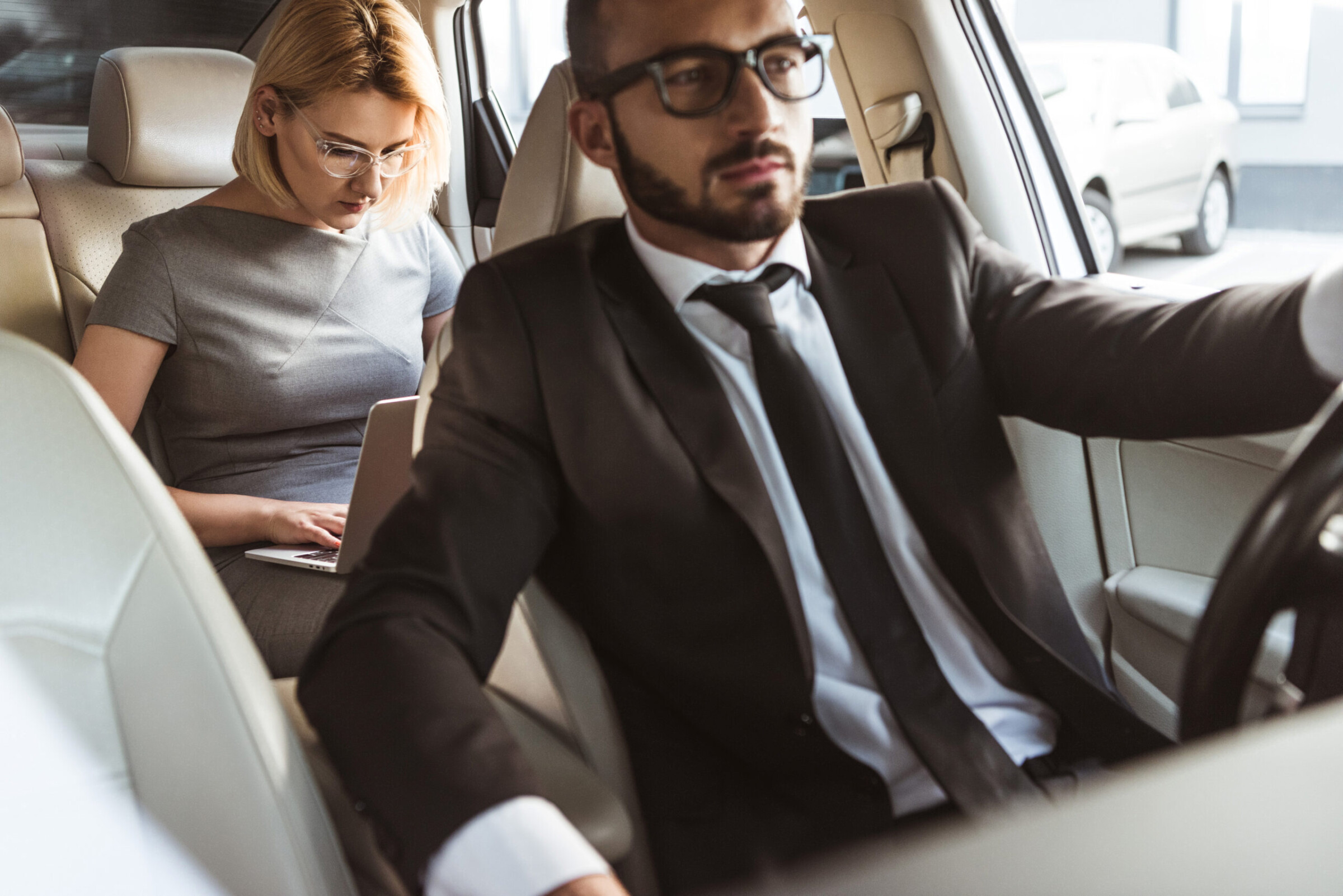 Handsome driver and beautiful businesswoman in car